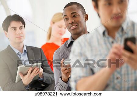 Casual businessmen using digital tablet and cell phone View Large Photo Image Stock Image - Casual businessmen using digital tablet and cell phone. Fotosearch