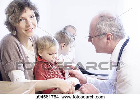 Picture - Child on mother's lap being examined by doctor. Fotosearch