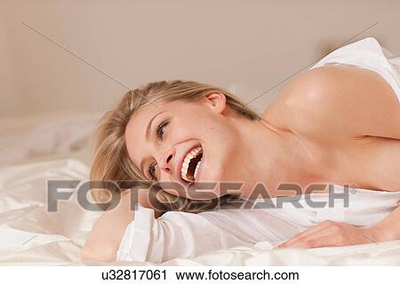 Close up portrait of a young blond woman lying on bed smiling View Large Photo Image Stock Image - Close up portrait of a young blond woman lying on bed smiling. Fotosearch
