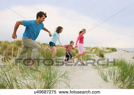 Stock Photography - Family holding hands and running at the beach. Fotosearch
