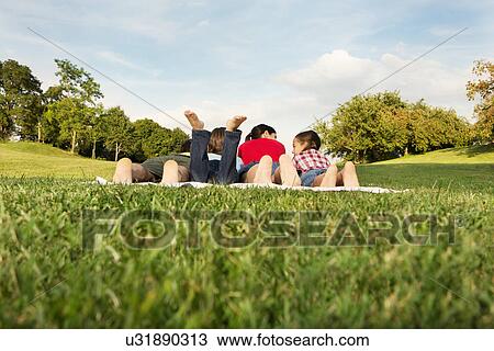 Family with two children lying on grass, rear view View Large Photo Image Stock Image - Family with two children lying on grass, rear view. Fotosearch