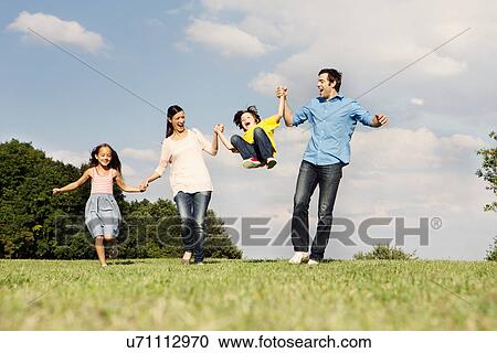 Family with two children, parents swinging boy View Large Photo Image Stock Image - Family with two children, parents swinging boy. Fotosearch