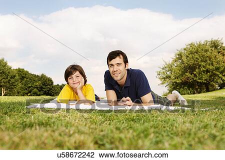 Stock Image - Father and son lying on blanket. Fotosearch