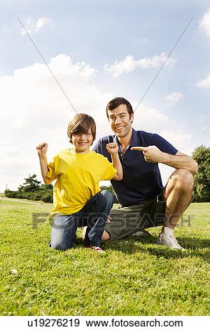 Father pointing at son lying flexing muscles View Large Photo Image Stock Photo - Father pointing at son lying flexing muscles. Fotosearch