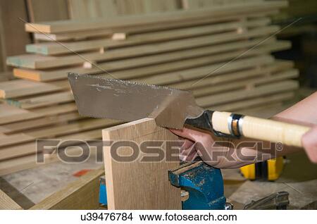 Picture - Female carpenter using ryoba (double blade) dozuki (japanese backsaw) to create joint. Fotosearch
