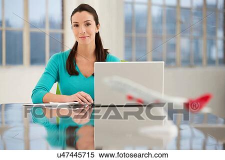Stock Photography - Female office worker sitting at desk with laptop. Fotosearch