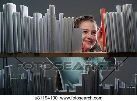 Stock Image - Girl choosing red book from bookshelf. Fotosearch