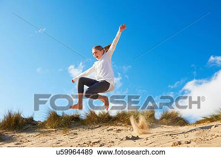 Stock Photo - Girl jumping on beach. Fotosearch