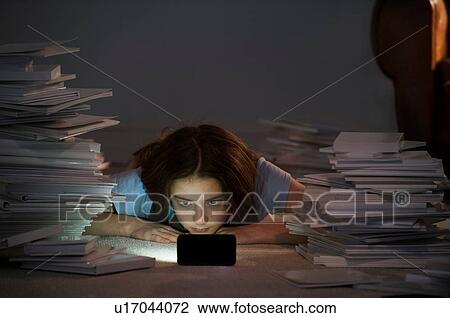 Girl lying on front watching cell smartphone surrounded by books View Large Photo Image Stock Image - Girl lying on front watching cell smartphone surrounded by books. Fotosearch