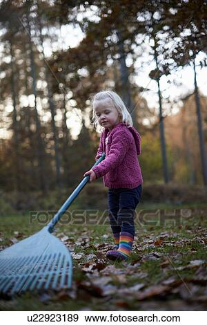 Girl raking leaves in forest View Large Photo Image Stock Photo - Girl raking leaves in forest. Fotosearch