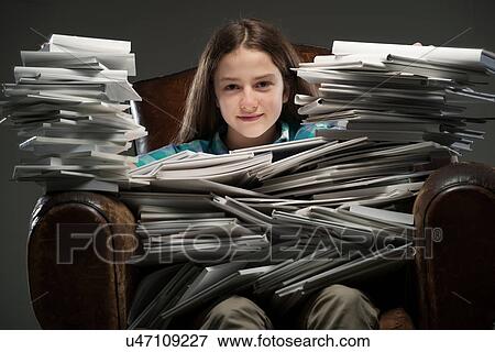Stock Photo - Girl sitting in leather armchair with piles of books, smiling. Fotosearch