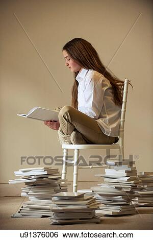 Girl sitting on chair reading book View Large Photo Image Stock Photograph - Girl sitting on chair reading book. Fotosearch