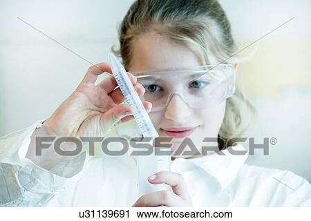 Stock Image - Girl wearing safety goggles doing science experiment. Fotosearch