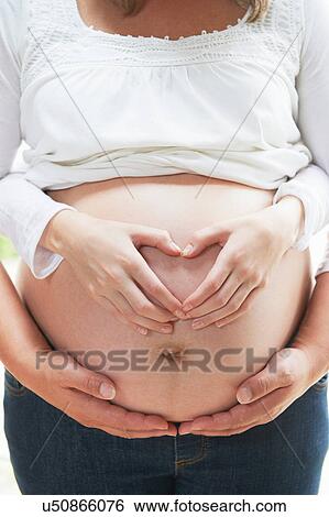 Hands in heart shape on pregnant woman's stomach View Large Photo Image Stock Photograph - Hands in heart shape on pregnant woman's stomach. Fotosearch
