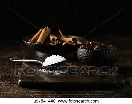 Stock Image - Ingredients to make an Irish dry cured spiced beef joint. Sea salt, cinnamon sticks and mixed spices on dark wooden surface. Fotosearch