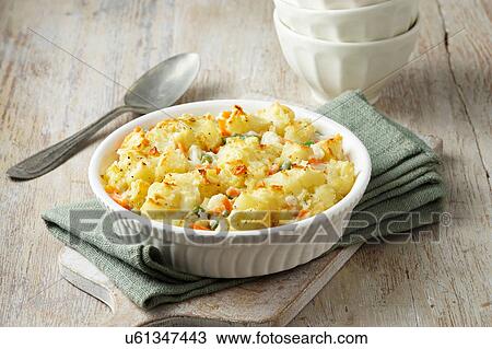 Stock Image - Large vegetable bake consisting of carrots, peas and beans with potato on green cloth. Fotosearch
