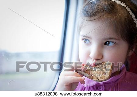 Stock Photo - Little girl on train, eating. Fotosearch