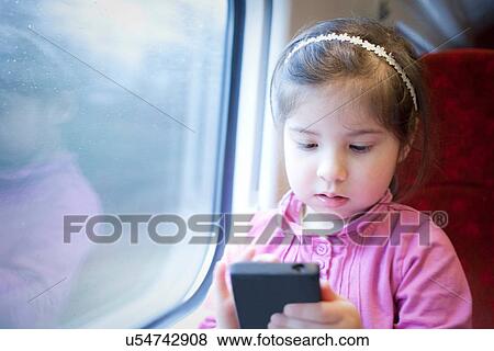 Little girl on train, playing game on smartphone View Large Photo Image Stock Photo - Little girl on train, playing game on smartphone. Fotosearch