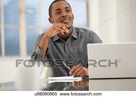 Stock Photography - Male office worker sitting at desk. Fotosearch