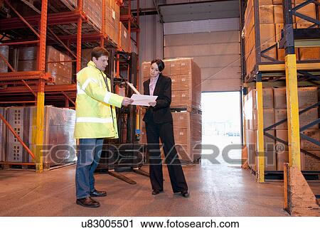Man and woman looking at paperwork in warehouse View Large Photo Image Stock Image - Man and woman looking at paperwork in warehouse. Fotosearch