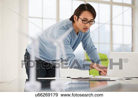 Man using laptop with models of wind turbines on desk View Large Photo Image Stock Photo - Man using laptop with models of wind turbines on desk. Fotosearch