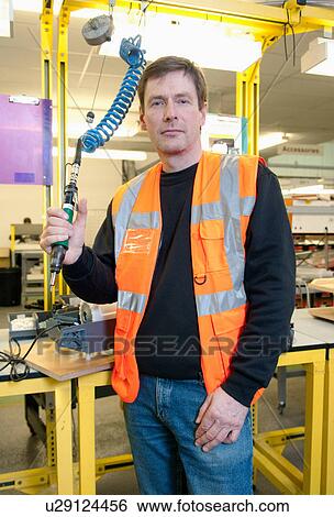 Stock Photograph - Man with machinery in electrical component factory. Fotosearch