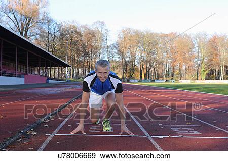 Mature man crouching on starting line of sports track View Large Photo Image Stock Photo - Mature man crouching on starting line of sports track. Fotosearch