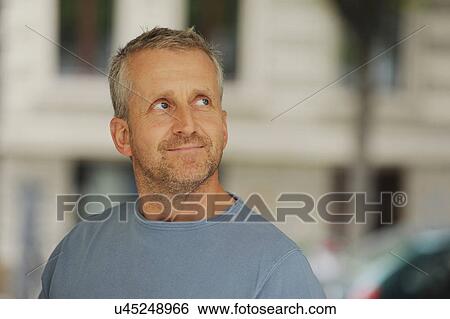Stock Photograph - Mature man looking away and smiling, indoors. Fotosearch