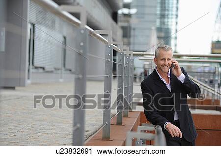 Stock Image - Mature man making cellphone call in financial district. Fotosearch