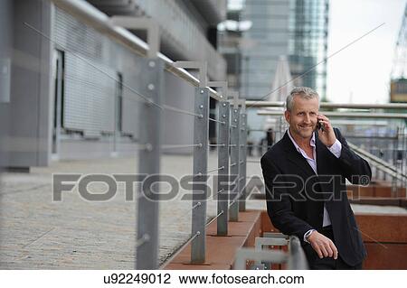 Stock Image - Mature man making cellphone call in financial district. Fotosearch