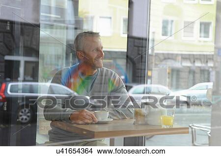 Picture - Mature man sitting in coffee shop. Fotosearch