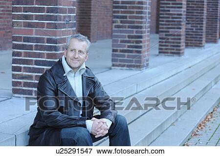 Stock Photo - Mature man sitting on steps outside. Fotosearch