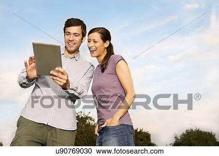 Stock Image - Mid adult couple using digital tablet. Fotosearch