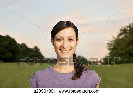 Stock Image - Mid adult woman looking at camera, smiling. Fotosearch