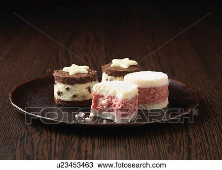 Stock Image - Mini tortes, raspberry and chocolate flavour on dark wooden plate. Fotosearch