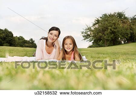 Mother and daughter lying on blanket looking at camera View Large Photo Image Stock Image - Mother and daughter lying on blanket looking at camera. Fotosearch