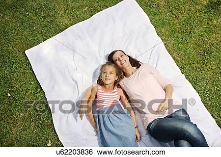 Stock Photograph - Mother and daughter lying on blanket, high angle. Fotosearch