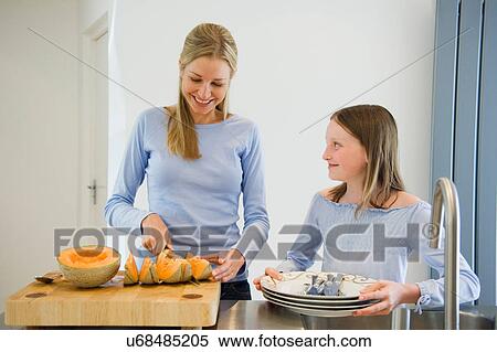 Stock Photography - Mother and daughter preparing melon. Fotosearch