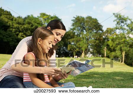 Stock Image - Mother and daughter reading book. Fotosearch