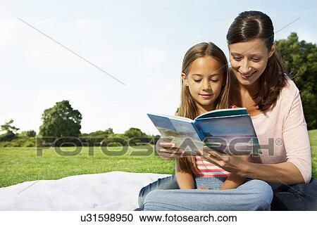 Stock Image - Mother and daughter reading book. Fotosearch