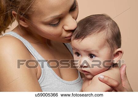 Stock Photograph - Mother kissing her baby girl. Fotosearch