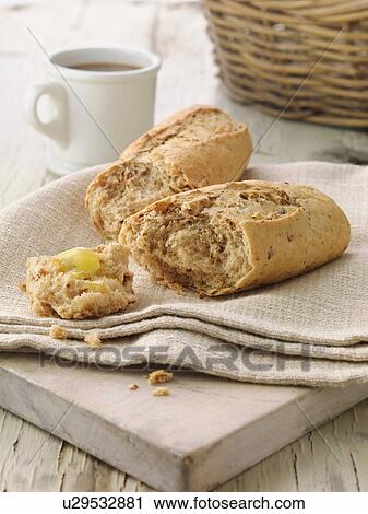 Stock Image - Multi grain baguette with butter on cream linen napkin. Fotosearch