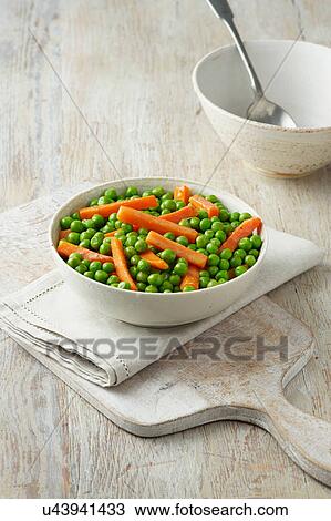 Stock Image - Peas and carrots in white bowl on cream cotton cloth. Fotosearch