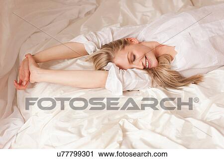 Portrait of a young blond woman lying on bed smiling View Large Photo Image Stock Image - Portrait of a young blond woman lying on bed smiling. Fotosearch