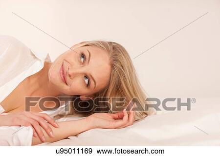 Portrait of a young blond woman lying on bed smiling View Large Photo Image Stock Photo - Portrait of a young blond woman lying on bed smiling. Fotosearch