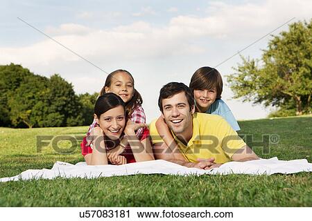 Portrait of family with two children lying on grass View Large Photo Image Stock Image - Portrait of family with two children lying on grass. Fotosearch