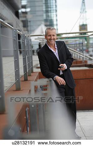 Portrait of mature man holding cellphone in financial district View Large Photo Image Stock Image - Portrait of mature man holding cellphone in financial district. Fotosearch