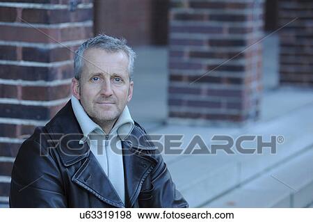 Stock Photo - Portrait of mature man sitting on steps. Fotosearch