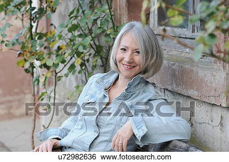 Stock Photograph - Portrait of senior woman relaxing in garden. Fotosearch