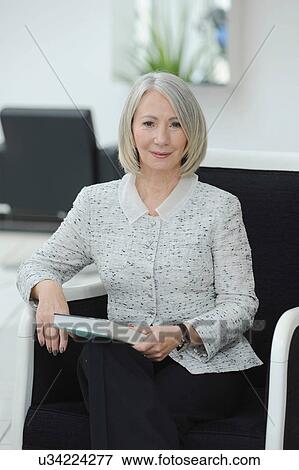 Portrait of senior woman sitting with book View Large Photo Image Stock Photo - Portrait of senior woman sitting with book. Fotosearch